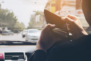 Man look at his empty wallet while driving car, dangerous behavior